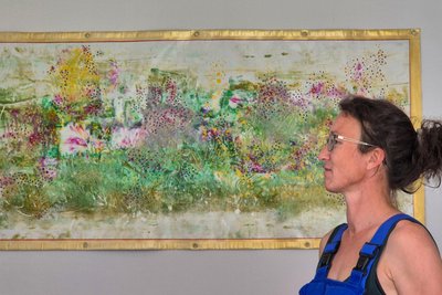 Katy Gluch vor ihrem Lieblingsbild, das im Wohnzimmer hängt. „Eine Theater-Plane lag auf dem Fußboden, ich rutschte darauf aus“, erzählt sie. Sie nahm Acrylfarbe und bemalte sie mit Händen und Füßen.