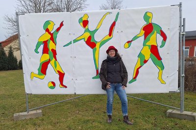 An mehreren Orten in Lichtenau hat Katy Gluch Transparente zum Kulturhauptstadtjahr aufgestellt, hier Fußballer, Turnerin und Tischtennisspieler als Symbol für Sportvereine in Lichtenau und dahinter eine Schwimmerin für das Sommerbad Garnsdorf.