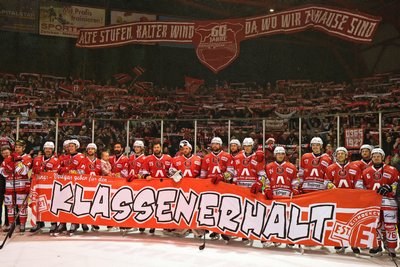 Das Team präsentiert sich mit dem Plakat „Klassenerhalt“ vor der Heine-Kurve.