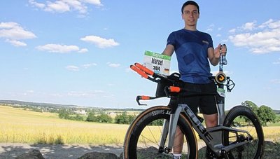 Marcel Ottiger präsentiert am Vogtlandblick, einem Aussichtspunkt in seinem Heimatort, Karbon-Rad, Startnummer und Finisher-Medaille von der Challenge in Roth. 