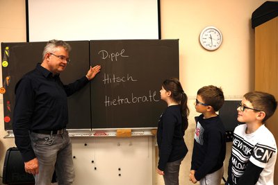 Steffen Kindt erklärt Anni, Immanuel und Lewin die drei Siegerworte vom diesjährigen Wettbewerb zum erzgebirgischen Wort des Jahres.