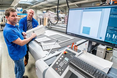Enrico Dost bespricht mit Betriebsleiter Tom Hertwig (v. l.) die Fertigung an einem digitalen Schneidsystem.