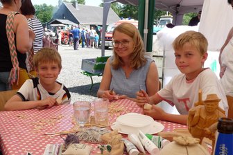 675 Jahre Lippersdorf: Das sind die schönsten Bilder des Jubiläums - Andrea Seifert mit ihren Söhnen Raphael und Benaja beim Schnitzen auf dem historischen Markt.