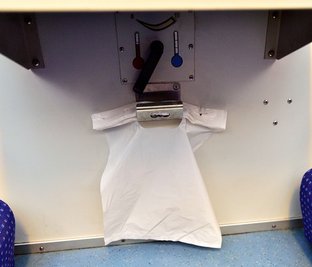 Plastiktüten ersetzen die Mülleimer an den Sitzplätzen. Darüber: der Heizungsregler. 