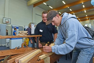 Griff zum Hobel: Richard Berge versucht sich am Holz, beraten von Azubi Tim Heller.
