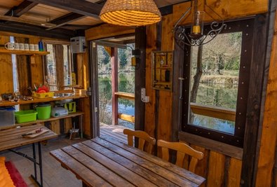 Blick in die Hütte mit Blick auf den Teich. Links die Küchenzeile, das Wasser dafür kommt über eine Fernleitung am Teichgrund. 