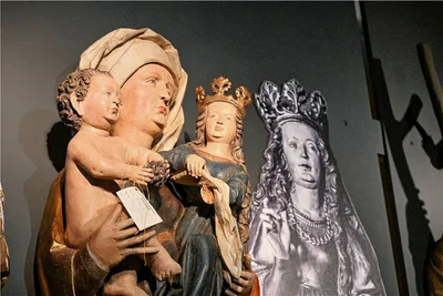 Das Foto zeigt die Figur der Heiligen Anna Selbdritt. Sie hält rechts ihre Tochter Maria und links ihr Enkelkind Jesus auf dem Arm. Die Figur wurde 1990 gestohlen. Die Zeichnung zeigt die verschollene Heilige Katharina. 