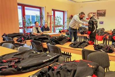 Auf den Tischen im Schulungsraum liegen Musterjacken und Musterhosen. 
