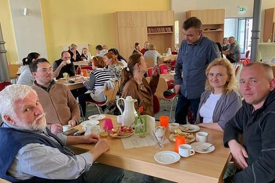 Jeden Mittwoch sitzen im Café Geflüchtete zusammen. In diesem Fall: Julia und Vitali Belakowitsch (rechts) im Gespräch mit Übersetzer Christoph Neumann aus Oberheinsdorf (links). In der Bildmitte Café-Leiterin Elke Göbel mit Uwe Schaller von der gleichnamigen Fleischerei. Dort arbeitet seit kurzem Valeri Kachlishvili, der hinten links seinen Kaffee schlürft. 