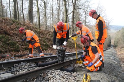 Entlang der Strecke der Drahtseilbahn werden die neu eingesetzten Kunststoffschwellen mit Schrauben fixiert.