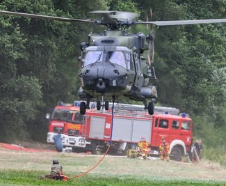 Auch die Bundeswehr unterstützt mit ihren Kräften die Brandbekämpfung im Naturpark - hier im Foto ein Hubschrauber, der mit einem Löschwasser-Außenlastbehälter am Ufer der Elbe abhebt. 