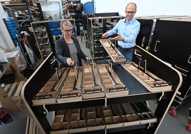 Angela Grimmer und Christoph Alt, Inhaber der Firma Ligenium, zeigen den hölzernen Transportwagen-Prototyp. Um ihre Geschäftsidee und ihre Forschungen der Wirtschaft schnell nahezubringen, gehen sie mit dem Modell zum Kunden. 