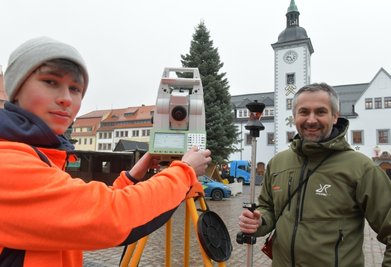 Alexander Neumeister (r.) und Azubi Julian Oertel waren am Donnerstag als Weihnachtsbaumvermesser unterwegs, hier mit ihrer Technik in Freiberg auf dem Obermarkt. Der Baum misst 14,48 Meter und ist damit der zweitgrößte in Mittelsachsen.
