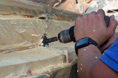 Das Blockhausbauen ist eine knifflige Sache, im Foto wird ein Stamm aufgespitzt.