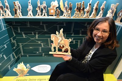 Anja Fiedler mit einer Holzfigur zum spielerischen Nachstellen der historischen Bergparade im Museumssaal „Freiberg im 17. & 18. Jahrhundert“.
