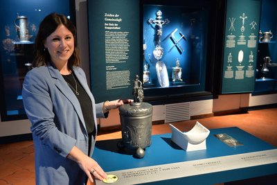 Die stellvertretende Museumdirektorin Anne Büning an der Taststation mit den Originalen im Schaukasten dahinter.