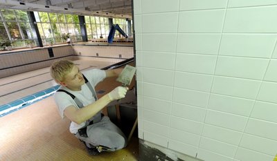 Baden nicht möglich: In der Schwimmhalle Gablenz werden zurzeit unter anderem die Toiletten- und Duschbereiche saniert. Im Bild: Lehrling Philipp Kahle von einer Chemnitzer Fliesenlegefirma verfugt eine neu geflieste Wand am Zugang zum Schwimmbecken.