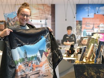 Janine Preißler, Mitarbeiterin der Tourist-Information im Silbermannhaus am Schlossplatz in Freiberg, stellt eine Welterbe-Picknickdecke vor. 