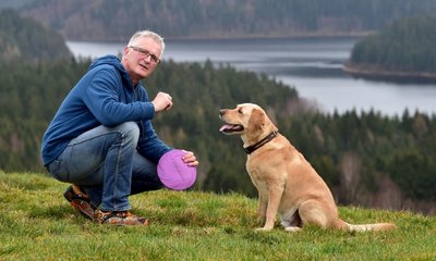 Vor dem Panorama der Talsperre Eibenstock ist Jörg Weißflog mit seinem siebenjährigen Labrador Billy in Hundshübel unterwegs.