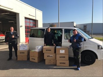 Daniel Schlefcke (l.), Leiter der Werksfeuerwer in Zwickau, und Werksfeuerwehrmann Ronny Dunger übergeben Atemschutzmasken, Schutzkittel und Schutzbrillen an Holger Eichmann von der Pleißentalklinik in Werdau.