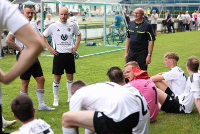 Schiedsrichter Michael Böhm überbringt den Erlbacher Spielern in der Halbzeitpause schlechte Nachrichten.