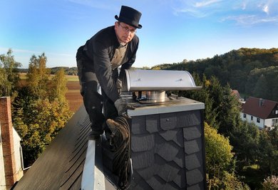 Schornsteinfeger Michael Huhn bei seiner Arbeit auf dem Dach eines Hauses im Hainichener Ortsteil Cunnersdorf.