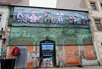 Ein Banner kündet an den Resten der Fassade des Hauses Petersstraße 19, dass hier das künftige Freiberger Welterbezentrum entstehen wird. Das Gebäude rechts daneben wird dabei mit einbezogen. 