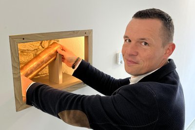 Frank Zwinscher mit der Dokumentenhülse in der Bruchsteinmauer.