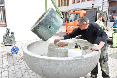 Am Klatschweiberbrunnen in Freiberg erfolgten Arbeiten, hier Steinmetzmeister Christoph Goral beim Aufsetzen des Brunnensockels auf das Becken.