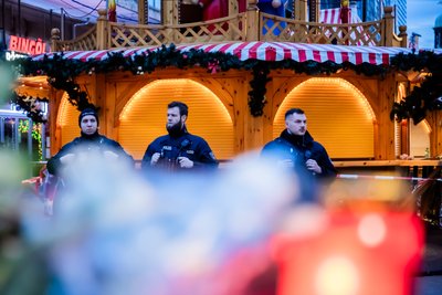 Polizisten sichern den Weihnachtsmarkt, wobei Kerzen vor ihnen brennen. Auf dem Weihnachtsmarkt in Magdeburg ist ein Autofahrer in eine Menschengruppe gefahren.