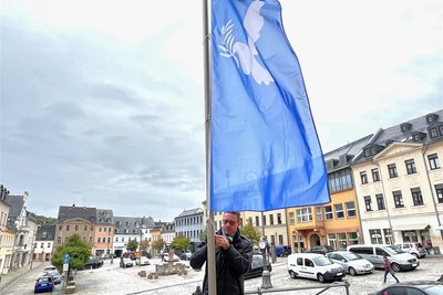 Oberbürgermeister Henry Ruß hisst die Fahne mit der Friedenstaube vorm Rathaus.
