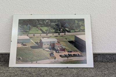 In einem Zimmer befindet sich ein älteres Luftbild des Areal.
