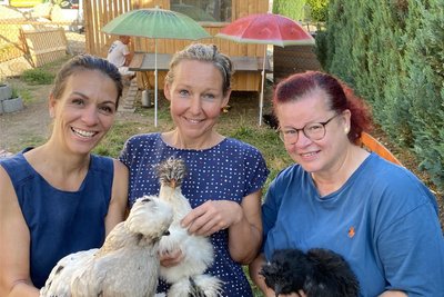 Die drei Frauen vom Lengenfelder Verein Herzkraftwerk im Hühnerhof des neuen Mitmachgartens am Tischendorfplatz. Von rechts: Daniela Scherzer (mit Huhn Minerva), Frederike Eisenkolb (Vesta) und Marlen Preßler (Gloria). Das Bild trügt nicht - die Seidenhühner sind einfach nur zum Knuddeln.