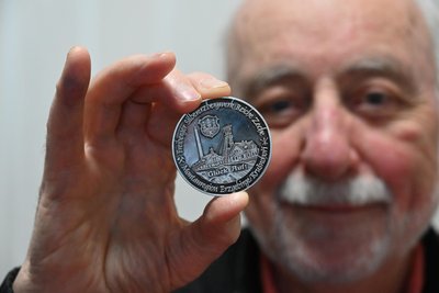 Helmut Herholz zeigt die Vorderseite der jüngsten Medaille zur Bergbaugeschichte des Erzgebirges mit der Beziehung von Freiberg und Chemnitz.