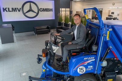 Geschäftsführer Tobias Degelmann auf einem Aufsitzrasenmäher, der von Kommunen auf großen Flächen wie Parks eingesetzt wird.