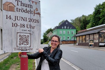 Quartiersmanagerin Kirsten Drechsel an einem der Werbeplakate für „Thum trödelt“.