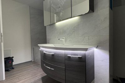 Freistehende Waschbecken-Wand mit Schmankerl dahinter - eine extra große Badewanne, an deren Kopfseite befindet sich die von der anderen Seite begehbare Duschkabine.