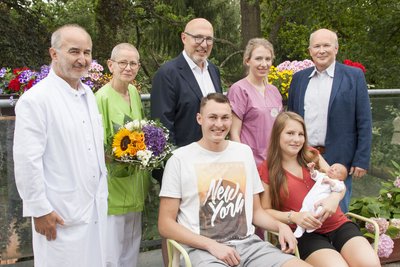 David Schmidt und Lea Charline Fankhänel mit Jubiläumsbaby Milas. Im Hintergrund: Dr. med. Gunter Leichsenring, Leiter der Geburtshilfe am DRK Krankenhaus Chemnitz-Rabenstein Stationsleiterin Geburtshilfe Grit Schuster, Verwaltungsratschef J. Michael Müller, Hebamme Marie-Theres Windisch und Geschäftsführer Dr.-Ing. Herbert Günther (von links.) 