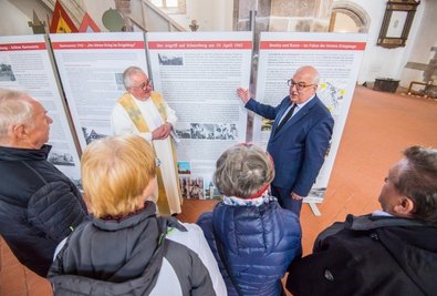 Steffen Ludwig, Bürgermeister von Reinsdorf (an der Tafel r.), erklärt Andachtsbesuchern und Pfarrer Frank Meinel historische Fakten. 