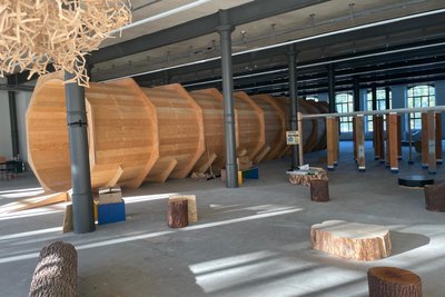 Eine nachgebildeter Stamm einer alten Eiche liegt zwischen den Eisensäulen. Erste Eindrücke von der Ausstellung "Alles Holz".