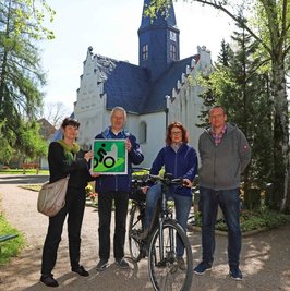 Kerstin Kracht überreichte Pfarrer Joachim Escher vor dem Langenhessener Gotteshaus das Signet "Radwegekirche". Ortsvorsteherin Jana Russ und Gunter Prem vom Kirchenvorstand waren dabei. 