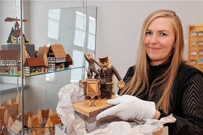 Museumsmitarbeiterin Vicky Seidel packt in einem Raum der Sonderausstellung eine Astarbeit aus, die zum Fundus des Museums gehört. Links sind einige der Miniaturhäuser zu sehen, die einen Großteil der Sonderschau prägen. 