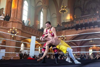 Wrestling in der St. Markuskirche: Mitten im Kirchenschiff wird der Ring zur Bühne, während Zuschauer auf Emporen und im Saal das ungewöhnliche Spektakel verfolgen.