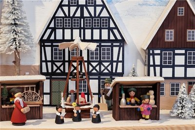 Häuschen und Weihnachtsmarktbuden dieser Dorfszene in einem Schwibbogen stammen aus der Firma Naumann Volkskunst in Rechenberg-Bienenmühle, die Figuren von anderen Herstellern. 