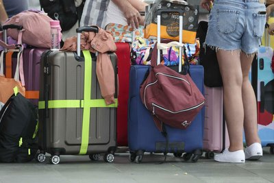 Flugreisende mit Kindern warten mit ihren Koffern am Check-In im Flughafen Leipzig-Halle. Wohin gehört das kleine Handgepäck? Die meisten beantworten diese Frage falsch. (Archiv)