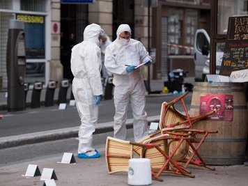 Polizisten in Schutzanzügen sichern vor dem Cafe Comptoir Voltaire in Paris Spuren.