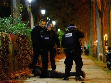 Polizisten haben in der Terrornacht von Paris einen Verdächtigen auf den Boden gezwungen.