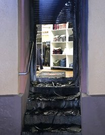 Einen Auto-Reifen hatten Unbekannte vor der Tür des Ladens entzündet.