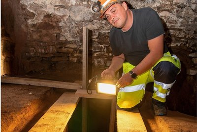 Steiger Sven Meyer von der Bergsicherung Sachsen leuchtet in den Kriechgang, den das Unternehmen im Keller unter dem Schillinghaus freigelegt hat. Ein Gitterrost soll diesen künftig sichern.