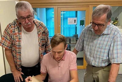 Christian Bauer, Marc Benedikt und Dr. Günter Hübsch (von links) beim Blättern in der Bauakte für das Kaiserliche Postamt. 